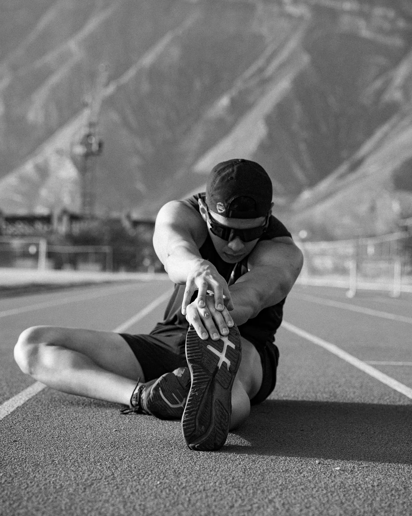 Atleta estirando la pierna sentado en la pista